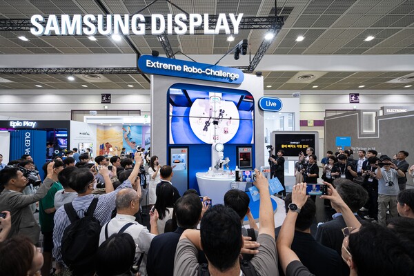 ▲'K-디스플레이 2024'에 참가한 삼성디스플레이 부스에서 관람객들이 폴더블 내구성을 테스트하는 로봇쇼를 관람하는 모습.
