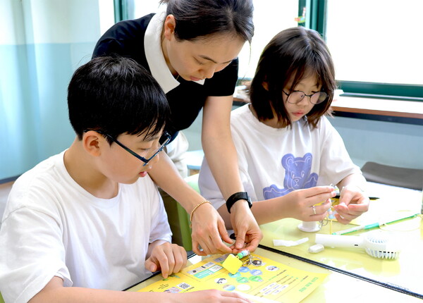 ▲일일 선생님이 된 LG화학 임직원이 아이들과 폐플라스틱으로 키링 만들기를 체험을 하고 있다.